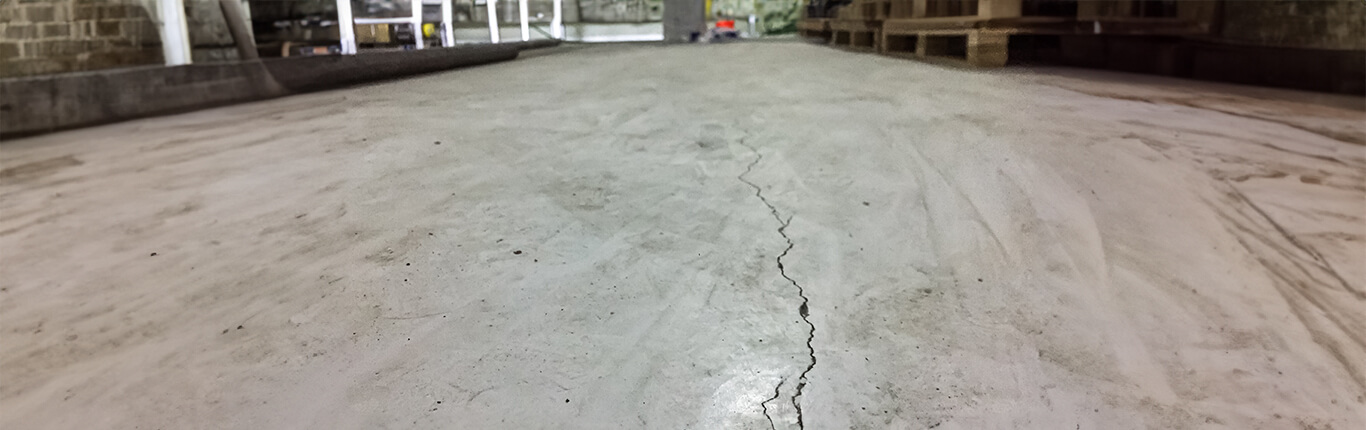 Industrial floor cracking with visible concrete damage and structural defects in a factory flooring system