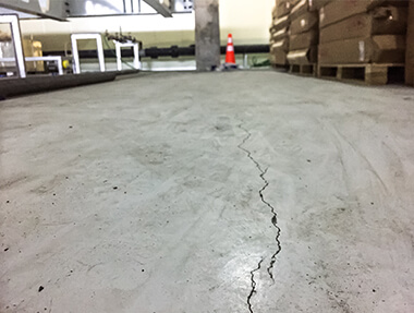 Industrial floor cracking with visible concrete damage and structural defects in a factory flooring system