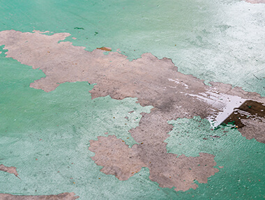 Epoxy floor peeling with visible surface damage, coating failure, and concrete floor defects in an industrial or commercial space